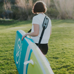 Person carrying paddle board with paddle board straps | Lifestyle