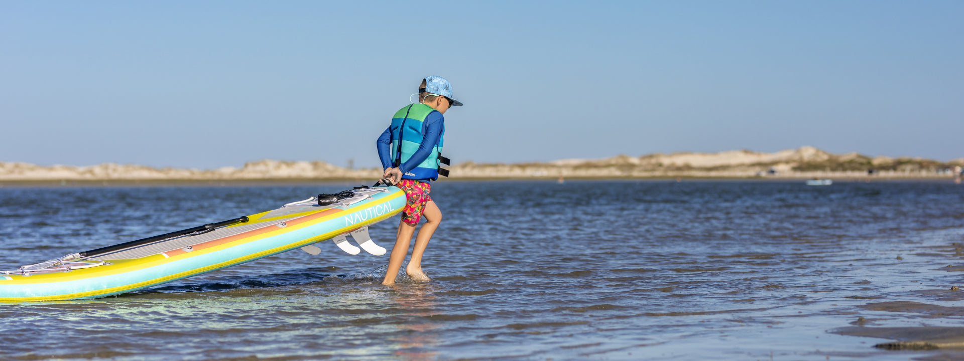 Little boy carrying a paddle board